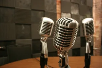 Three vintage microphones on a table in a recording studio
